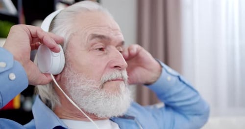 Senior Man Enjoys Music with Headphones Indoors