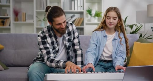 Bearded Man and Teen Girl Play Electric Piano Together