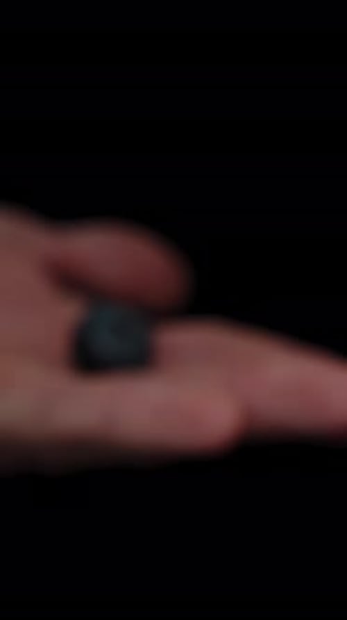Vertical video. Slowly emerging from afar, a solitary blueberry appears on a man's palm. Close-up.