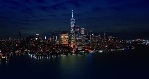Approaching dazzling skyline of Manhattan at night. Overcast sky above the scenery.