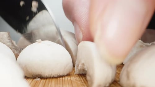 A girl cuts champignons in half, close-up.