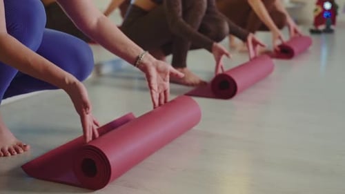 Group of People Rolling Up Yoga Mats After a Class Session in a Studio