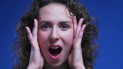 Woman reacting with shock and surprise, close-up face of an amazed female person in 20s