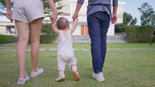 Close up of parents lovingly care for their baby boy outdoors in park.