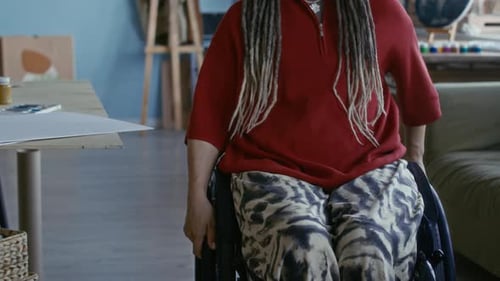 Young Female Artist with Disability Putting Blank Canvas on Easel in Studio