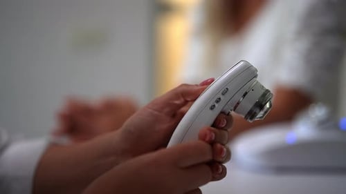 Woman Holding Skin Analysis Tool in Clinic