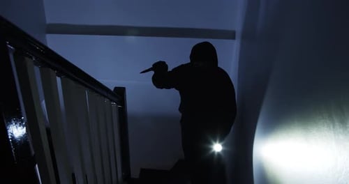 Silhouette Figure with Knife Climbing Dark Stairs