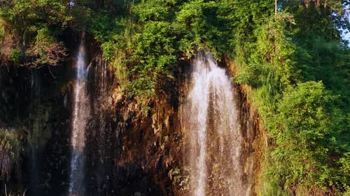 Der natürliche Wasserfall, der den Berg hinunterfließt, wird von der Abendsonne beleuchtet. Zeitlupe.