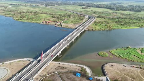 Aerial view of vehicles crossing a bridge over a large river. Bridge on the rural Indonesia. 4K dron