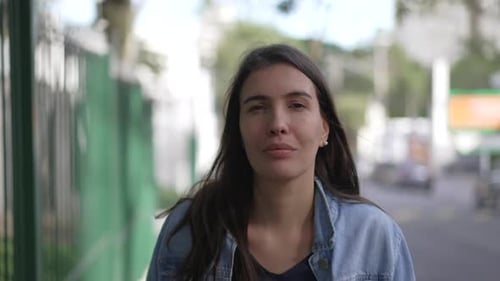 Confident happy woman walking forward in street looking at camera. Person in 30s portrait face