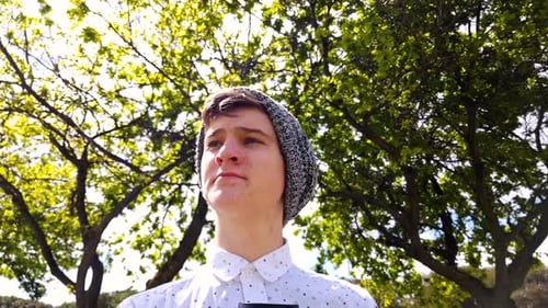 Young Man Drinking Beverage in Park on Sunny Day