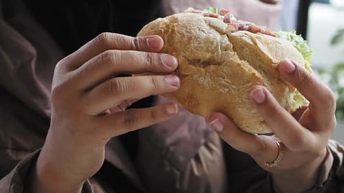 Hand Holding Beef Burger on Table Close Up