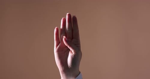 Frau zeigt Help-Me-Geste auf beigem Hintergrund, Nahaufnahme