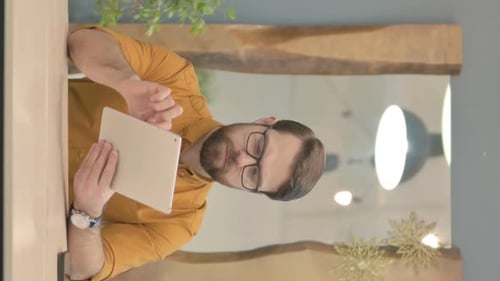 Man Using Silver Tablet at Table Indoors