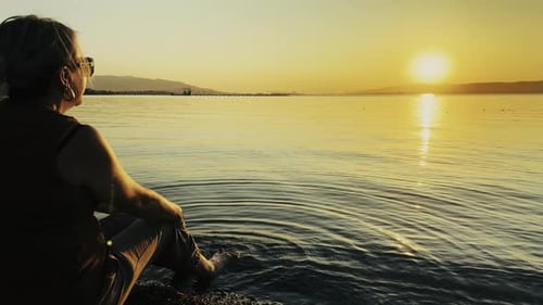 Woman With Her Feet In The Sea Looks At The Sunset 2