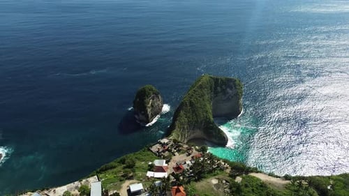Drone footage capturing a wide aerial orbit of Kelingking Beach in Bali, Indonesia, highlighting the