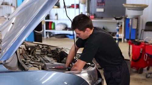 Closeup of a Worker a Repairman Repairing a Car The Open Hood of the Car in the Repair Garage