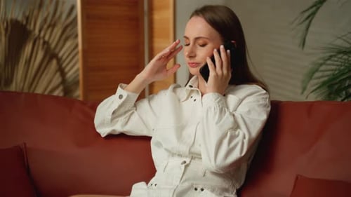 Worried Woman Talking on Phone on Couch