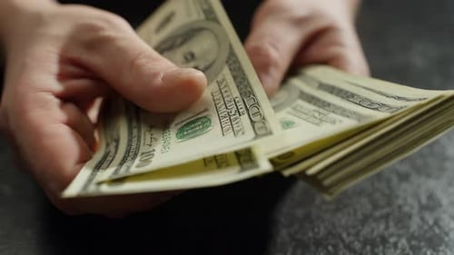 Hands Counting Stacks of Hundred Dollar Bills