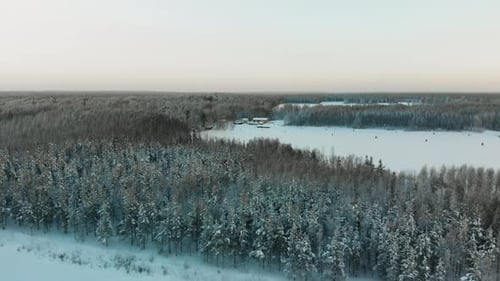Aerial. tracking, drone shot, over a frozen, snowy river, overlooking a island full of frosty forest