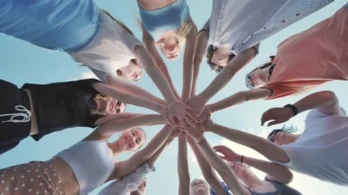Group of Young Women is Joining Hands in a Circle Outdoors Symbolizing Their Unity and Teamwork