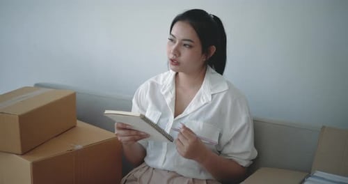 Woman with Notebook Writing Next to Boxes