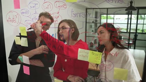 Team Brainstorming Together Using Sticky Notes on Glass