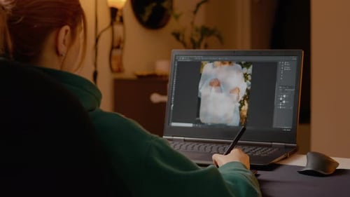 Woman editing photos with graphics tablet in home studio