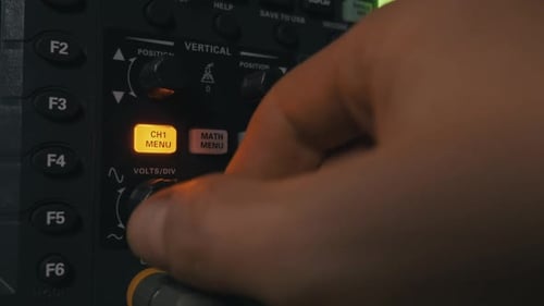 Technician Calibrating Digital Oscilloscope Controls In Electronics Lab