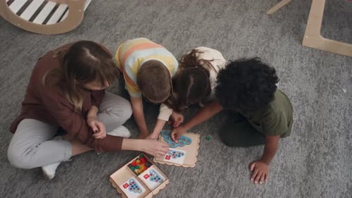 Children and Teacher Playing Education Game Together Indoors