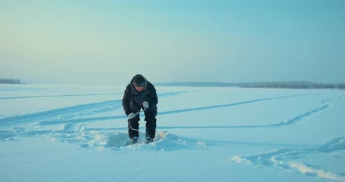 Eisbohren aus gefrorenem Fluss zum Eisfischen Ganzkörperporträt von Fisher in Morning Prores
