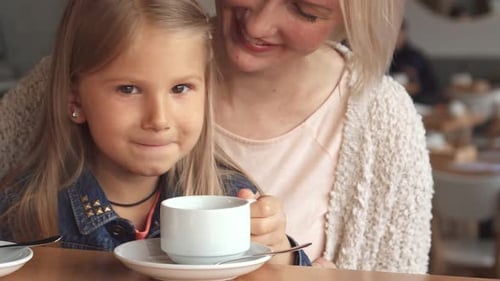 Little Girl Enjoys a Delightful Sip of Tea at the Cozy Cafe