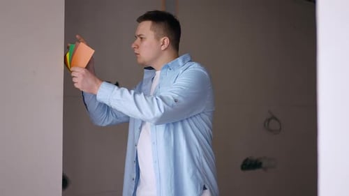 Side View Concentrated Brunette Man Choosing Walls Color Examining Palette Standing in New Apartment