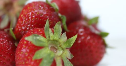 Many fresh ripe strawberries on white background, rotating