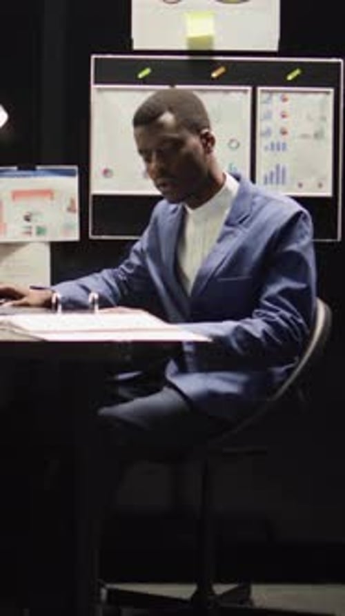 Man Reviews Documents in Darkened Office Setting