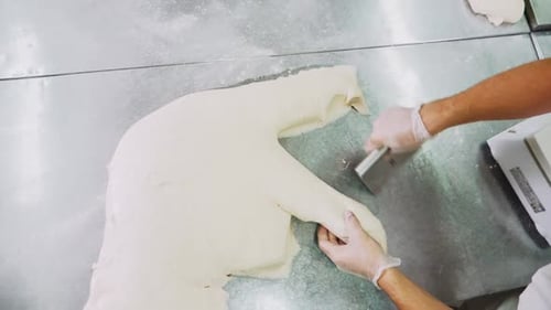 Baker Cuts Dough and Puts Onto Scale in Bakery Upper View