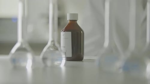 Braune Flasche mit durchsichtigen Laborflaschen auf einem weißen Tisch in einem Labor