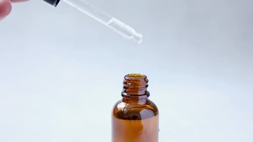 Liquid Drops from Pipette into Amber Bottle