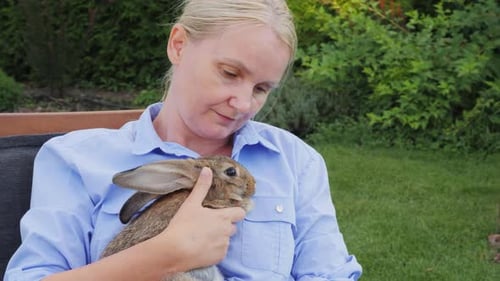 Woman Cuddles Brown Rabbit in Lush Garden