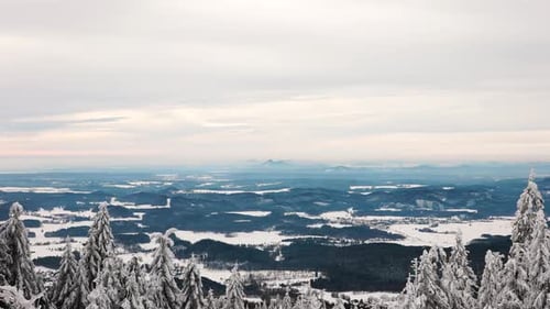 Scenic far view from hill over rugged countryside terrain, snowy treetop