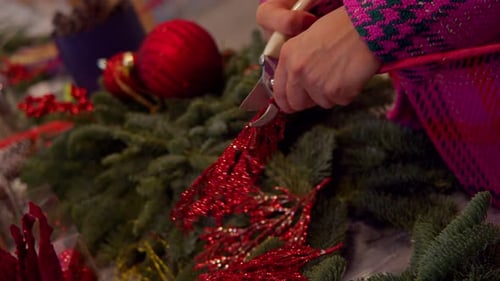 Female Florist Uses Scissors to Cut Glitter Twig Branch in Order to Make New Year Wreaths and