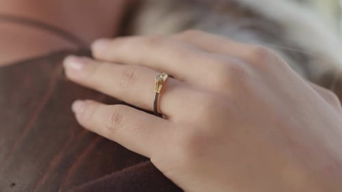 Frauenhand mit einem zarten, modernen Diamant-Verlobungsring. Schwarzes Gold.