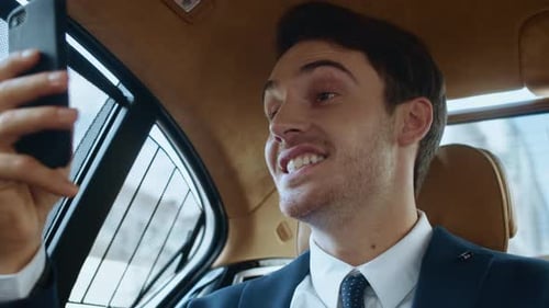 Man in suit smiles during video call in car