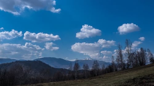 Zeitraffer: Malerischer Blick auf sanfte Hügel vor einem strahlend blauen Himmel mit flauschigen weißen Wolken