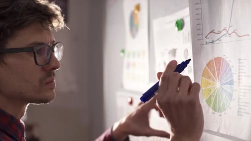 Young Adult Man Analyzes Charts in Office