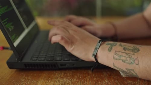 Programmer Types Code on Laptop Fingers Rapidly Pressing Keys In Focus Coding on Screen Tattooed