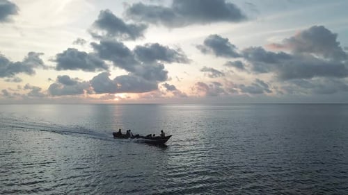 Suivi aérien d'un bateau en bois dans la baie de Banda Neira au coucher du soleil.