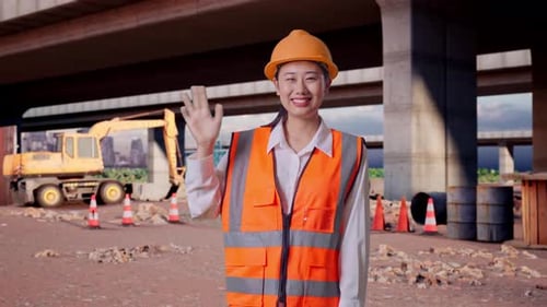 Asian Female Engineer Smiling To Camera And Waving Hand Saying Bye At Building Site