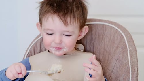 Toddler Eating Messy Meal in High Chair