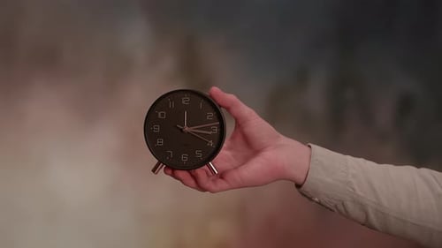 Hand Holding a Black Analog Alarm Clock